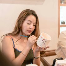 pexels-asadphoto-30225357 Une jeune femme peignant des fleurs sur une tasse