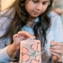 pexels-asadphoto-30225358 Une jeune femme peignant des fleurs sur une tasse
